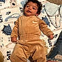Kamari joined the competition — help win amazing prizes! baby, infant, child, velour_outfit, brown_clothing, dinosaur_blanket, patterned_blanket, carpet, curly_hair, person, ripped_jeans, leg, floor, indoor, cute, lying_down, looking_away, hand, footwear_absent, soft_texture