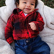 Kamari is registered to the contest to win money with this photo: baby, infant, smile, plaid_shirt, denim, jeans, blanket, curly_hair, outdoor, grass, cute, happy, child, cozy, clothing, portrait, toddler, warm, casual_wear, person
