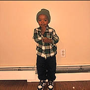 Darius Warren joined the competition — help win amazing prizes! beanie, black_pants, casual_clothing, child, cute, expression, fashion, floor, home_interior, indoor, person, plaid_shirt, portrait, sneakers, standing, thinking, toddler, wall_outlet, wooden_floor, young_child
