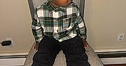Darius Warren is registered to the contest to win money with this photo: beanie, black_pants, casual_clothing, chair, child, electronic_charger, flooring, footwear, headwear, indoor, nike_sneakers, plaid_shirt, portrait, power_outlet, serious_expression, side_view, sitting, wall, wooden_floor, young_boy