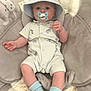 Axel is registered to the contest to win money with this photo: animal_print, baby, blanket, blue_socks, child, comfort, cushion, cute, dinosaur_print, face, hat, indoor, infant, pacifier, plush, relaxing, romper, seat, soft, young