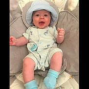 Axel joined the competition — help win amazing prizes! baby, baby_seat, blue_socks, child, clothing, cushion, cute, face, giraffe_print, happy, hat, indoor, infant, lying_down, onesie, pacifier, pattern, person, portrait, smiling