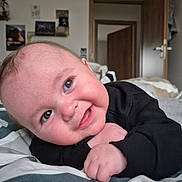 Thélio participe au concours pour gagner de l'argent avec cette photo : baby, bed, blanket, child, clothing, cozy, cute, decoration, door, eyes, face, hands, happy, indoor, infant, lying_down, portrait, room, smile, wall