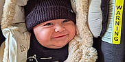 Thélio a rejoint le concours — aidez-le/la à gagner de superbes lots ! baby, car_seat, child, closeup, clothing, cozy, cute, face, fur_hood, happy, hat, indoor, infant, knitted_hat, person, portrait, seat_belt, smiling, warm, warning_label