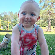 Jamison is registered to the contest to win money with this photo: baby, child, smile, face, blue_eyes, tank_top, striped_clothing, rhino_graphic, grass, outdoor, park, trees, playground, sunny, daylight, person, cute, cheeky, closeup, sitting