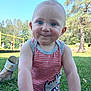baby, child, smile, face, blue_eyes, tank_top, striped_clothing, rhino_graphic, grass, outdoor, park, trees, playground, sunny, daylight, person, cute, cheeky, closeup, sitting
