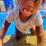 toddler, child, wet, water, playground, crawling, tongue_out, smiling, sunlight, outdoor, fun, happy, face, curly_hair, clothing, short_sleeve, blue, yellow, person, cute