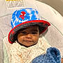 baby, child, hat, bucket_hat, spiderman, pajamas, toy_story, plush_toy, blue, smile, face, indoor, seat, cushion, cute, infant, clothing, portrait, cozy, relaxed
