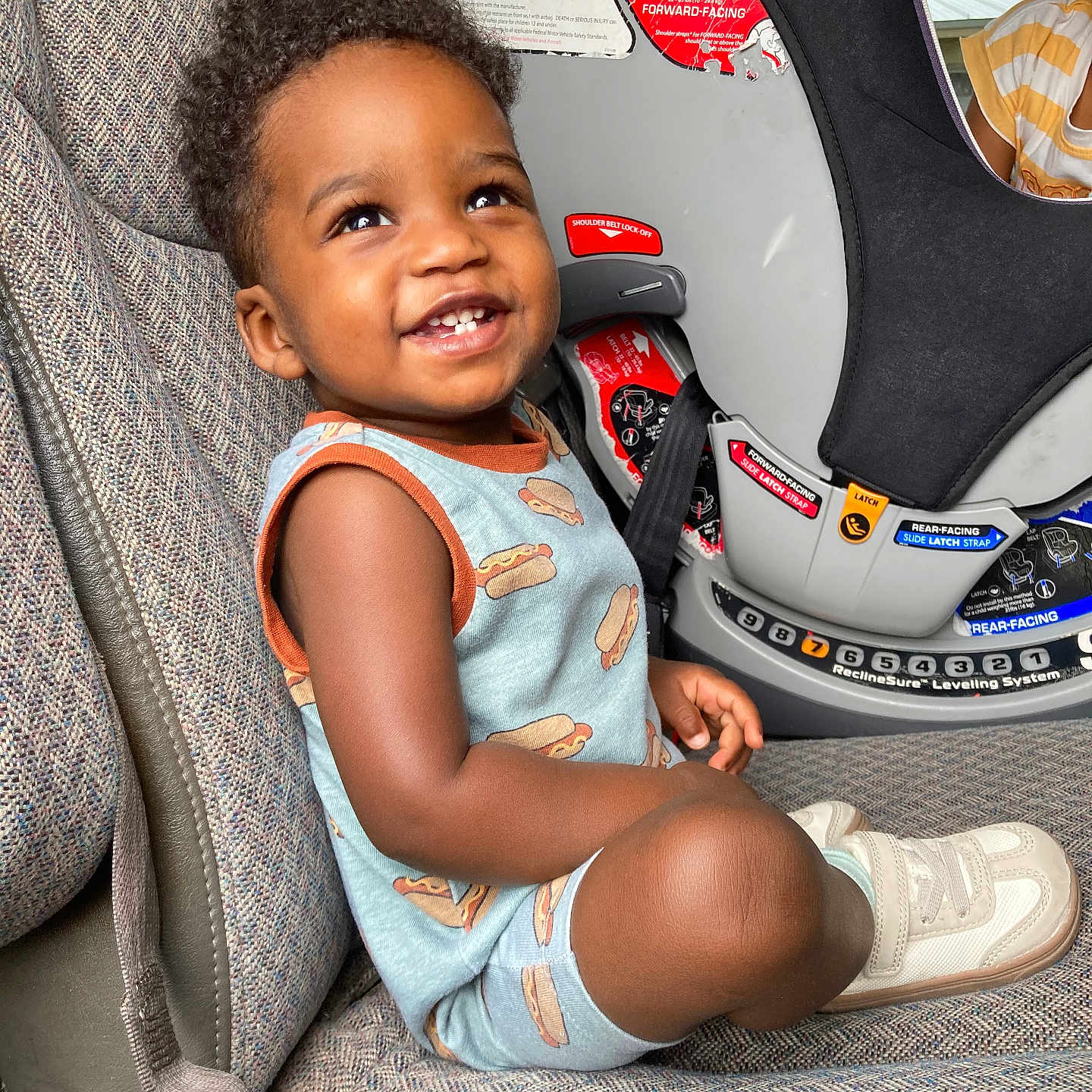 Anthony joined the competition — help win amazing prizes! baby, car_interior, car_seat, child, clothing, curly_hair, cute, feet, happy, hot_dog_print, indoor, looking_up, person, portrait, safety, seat, seatbelt, smiling, sneakers, toddler