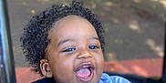 Anthony is registered to the contest to win money with this photo: child, toddler, smiling, curly_hair, blue_shirt, mickey_mouse, outdoor, stroller, happy, baby, person, clothing, playful, laughing, cute, seat, daylight, expression, portrait, fun