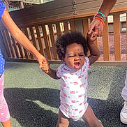 Anthony joined the competition — help win amazing prizes! toddler, child, holding_hands, playground, outdoor, determined, sunlight, footwear, clothing, person, support, expression, hair, legs, hand, fence, shadow, sneakers, ground, daytime