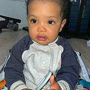 Kaïna participe au concours pour gagner de l'argent avec cette photo : toddler, child, indoor, face, hands, clothing, playmat, toy, expression, person, sitting, floor, window, hair, topknot, sleeves, pants, light, focus, curious