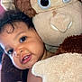 baby, child, plush_toy, monkey, stuffed_animal, face, portrait, cuddly, cute, soft_toy, smiling, indoors, closeup, pink_background, childhood, happy, warm, fuzzy, toy, snuggle
