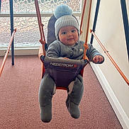 Sunni joined the competition — help win amazing prizes! baby, indoor, swing, winter_clothing, hat, smile, carpet, window, glass, rope, seat, child, face, person, play, cozy, warm, cute, expression, furniture