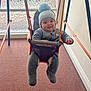 baby, indoor, swing, winter_clothing, hat, smile, carpet, window, glass, rope, seat, child, face, person, play, cozy, warm, cute, expression, furniture