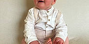 Sunni is registered to the contest to win money with this photo: baby, child, infant, sitting, white_shirt, suspenders, barefoot, couch, beige, soft_texture, happy, portrait, indoors, cute, smile, hands, feet, young, curious, light