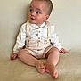 Sunni joined the competition — help win amazing prizes! baby, child, sitting, beige_clothing, suspenders, shorts, curious, soft_surface, innocence, portrait, indoor, cute, small_hands, barefoot, looking_away, light_skin, short_hair, buttoned_shirt, neutral_background, young_child