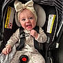 baby, infant, baby_girl, headband, bow, car_seat, safety_harness, onesie, blanket, smile, blue_eyes, cheek, hand, red_button, warning_label, striped_canopy, closeup, adorable, happy, portrait