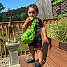 Daysean joined the competition — help win amazing prizes! child, toddler, outdoor, zoo, giraffe, statue, snacking, cracker, backpack, green_bag, portrait, standing, playground, wooden_deck, fence, vegetation, sunny, travel, animal_exhibit, family_outing