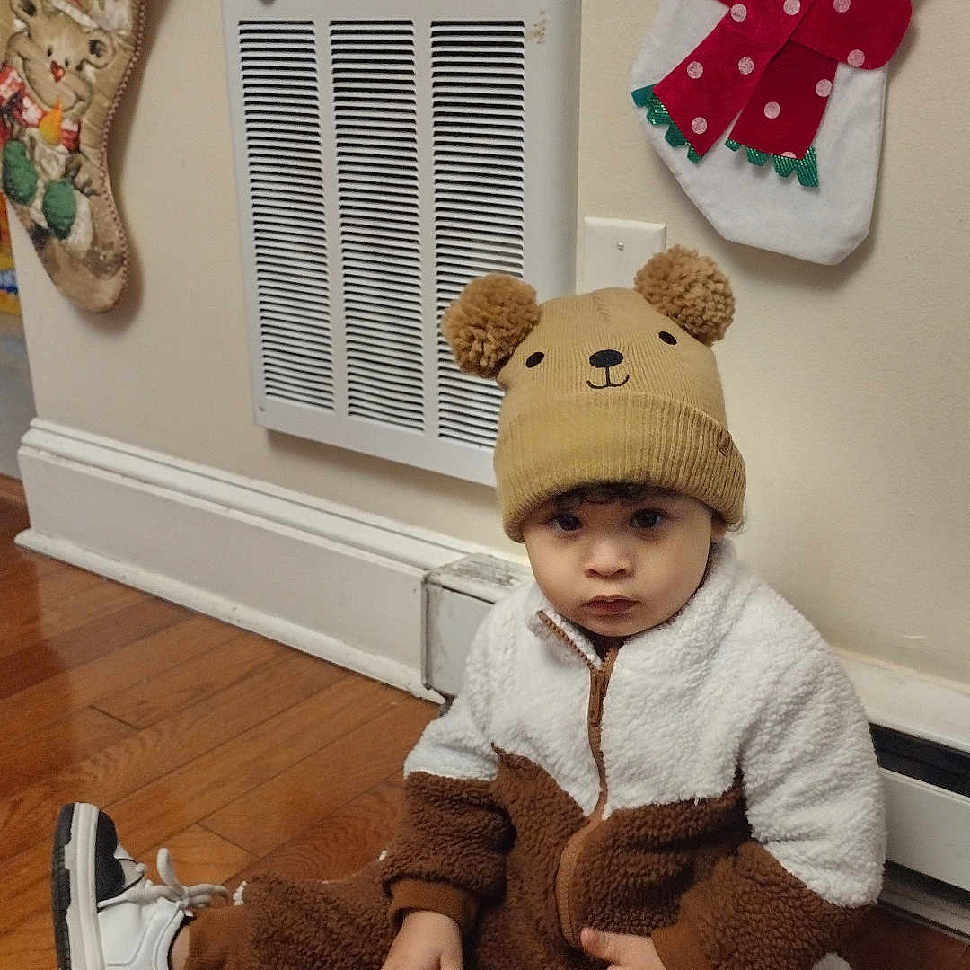 Daysean joined the competition — help win amazing prizes! child, toddler, portrait, sitting, indoors, holiday, christmas, snowman, stocking, bear_hat, bear_costume, winter_clothing, fleece, sneakers, hardwood_floor, wall, vent, festive, serious_expression, full_body