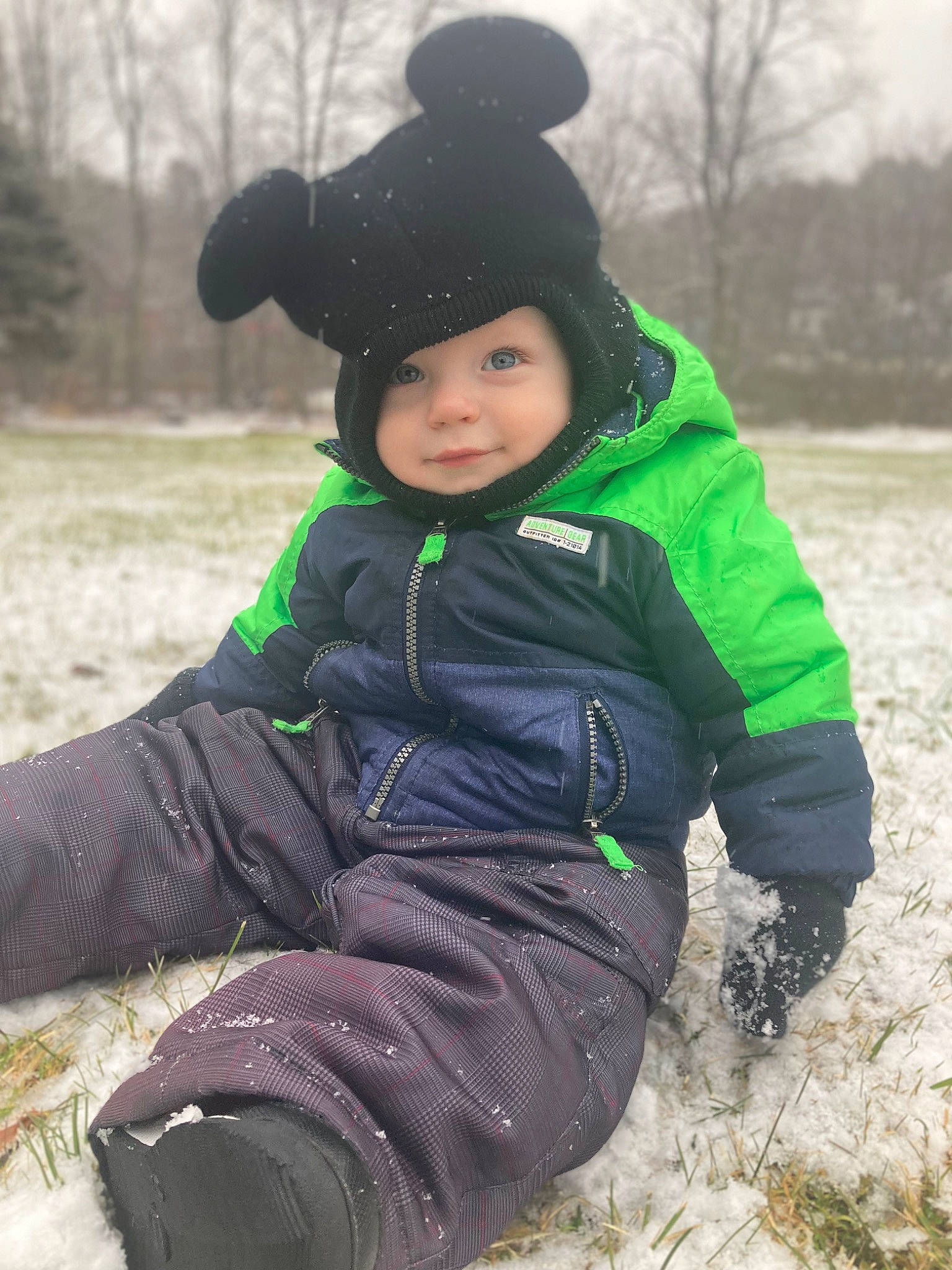 Calvin is registered to the contest to win money with this photo: baby_toddler_clothing, bicycle_helmet, cap, face, freezing, glove, grass, happy, headwear, helmet, jacket, outerwear, people_in_nature, person, personal_protective_equipment, recreation, sleeve, snow, toddler, tree