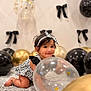baby, child, crawling, balloon, black_balloon, gold_balloon, clear_balloon, headband, smiling, indoor, decorations, bow, white_wall, floor, cute, festive, happy, portrait, infant, celebration