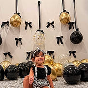 Iyrashambavi joined the competition — help win amazing prizes! baby, child, smile, balloon, black_bow, gold_balloon, black_balloon, transparent_balloon, headband, patterned_blanket, sitting, happy, indoor, decorations, party, cute, fashion, infant, portrait, celebration