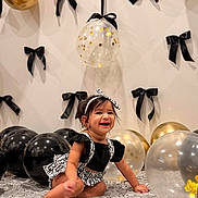 Iyrashambavi joined the competition — help win amazing prizes! baby, child, smiling, balloon, black_bow, gold_balloon, clear_balloon, patterned_cloth, headband, black_top, white_skirt, sitting, celebration, indoor, decor, happy, portrait, cute, person, festive