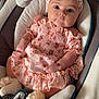 baby, infant, pink_dress, headband, plush_toy, baby_seat, cushion, bracelet, flower_pattern, soft_toy, indoors, cute, child, portrait, baby_clothes, comfortable, sitting, adorable, young_child, baby_accessories