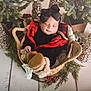 baby, basket, boots, black_bow, closed_eyes, cozy, decorations, evergreen, festive, floor, glitter, holiday, indoor, infant, plaid, red, sleeping, winter, wood_floor, wreath