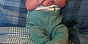 Noah is registered to the contest to win money with this photo: baby, infant, plaid, quilt, bed, wood, headboard, clothing, socks, person, child, indoor, resting, cute, young, portrait, fabric, pattern, cozy, furniture