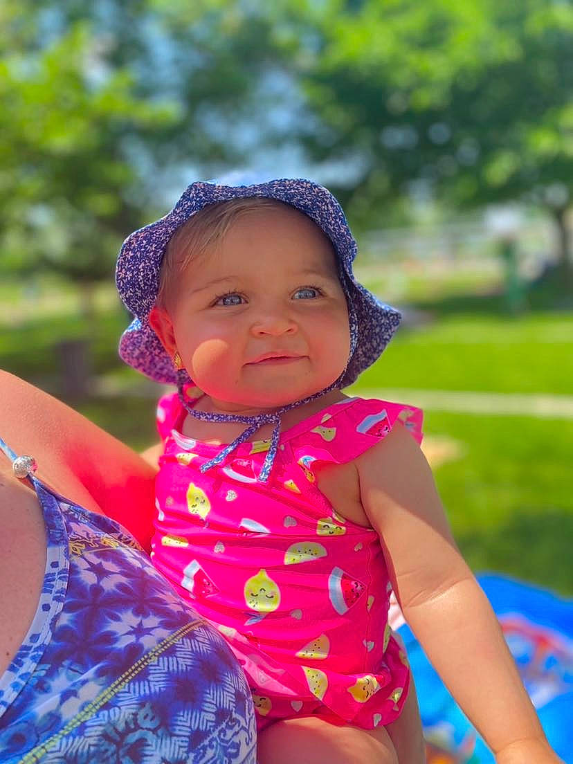 Mia a rejoint le concours — aidez-le/la à gagner de superbes lots ! baby, baby_toddler_clothing, blue, cap, child, clothing, fun, grass, happy, hat, headwear, leisure, magenta, people_in_nature, person, pink, smile, summer, sunlight, toddler