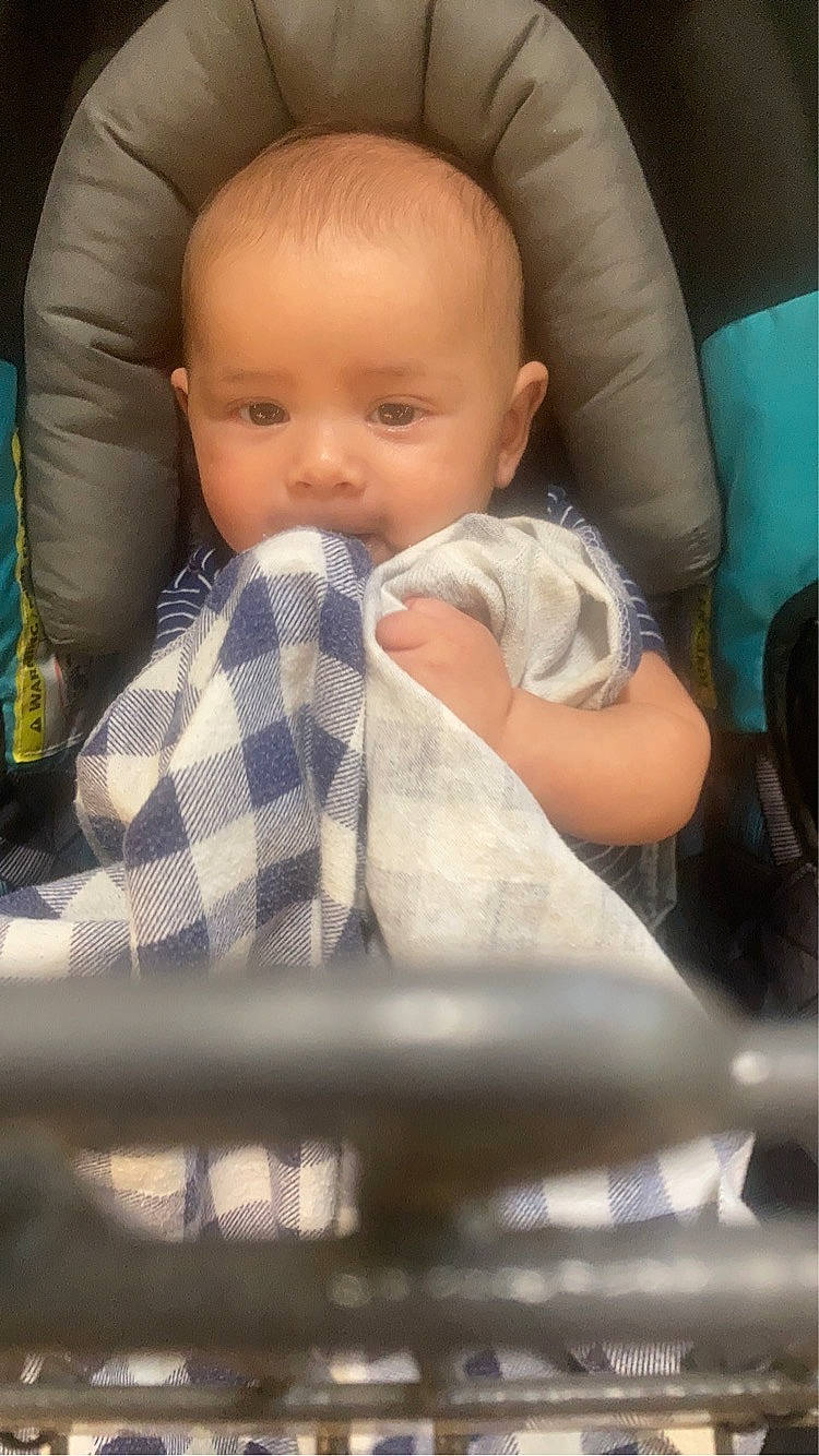 Miguel is registered to the contest to win money with this photo: baby, baby_in_car_seat, baby_products, baby_safety, baby_toddler_clothing, cheek, child, chin, comfort, finger, head, linens, mouth, nail, person, plaid, sitting, skin, tartan, thumb