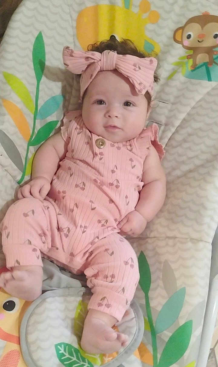 Novian is registered to the contest to win money with this photo: baby, child, infant, pink_clothing, headband, bow, lying_down, playmat, animal_pattern, leaf_pattern, cute, portrait, face, feet, hand, soft_toys, indoor, childcare, smiling, comfortable