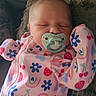 baby, infant, sleeping, pacifier, onesie, colorful_clothing, patterned_clothing, flowers, rainbows, strawberries, cherries, couch, cushion, resting, peaceful, indoors, close_up, portrait, child, cute