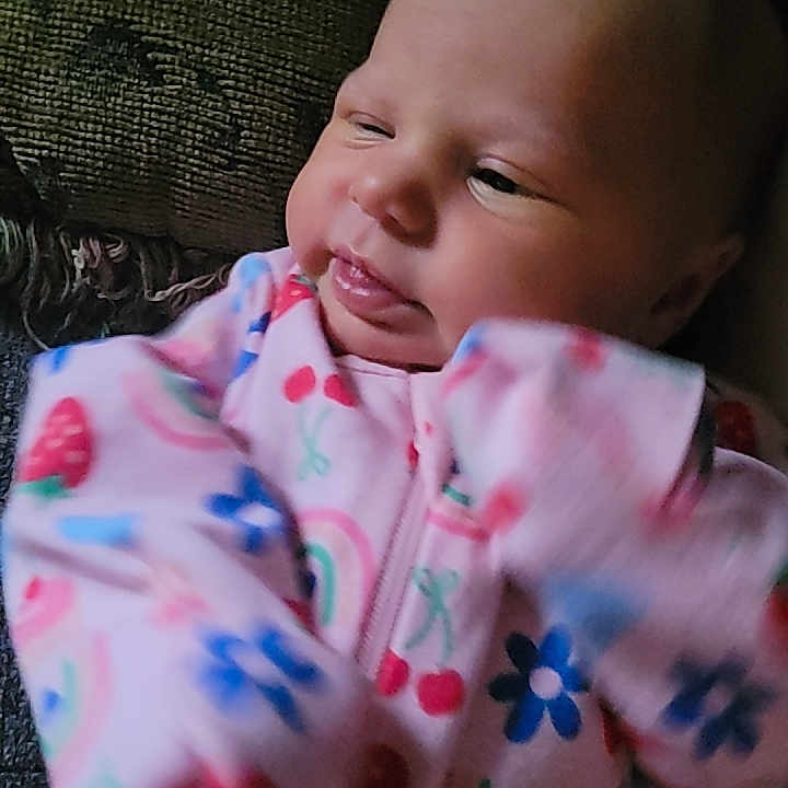 Adelyn joined the competition — help win amazing prizes! baby, infant, onesie, colorful_clothing, patterned_clothing, face, expression, hand, motion_blur, person, child, indoor, couch, upclose, portrait, cute, holding, pink, blue, green