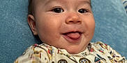 Elijah joined the competition — help win amazing prizes! baby, blue_couch, child, closeup, couch, cute, dog_pattern, expression, face, hair, happy, indoor, infant, onesie, person, playful, relaxed, smiling, tongue_out, young_child
