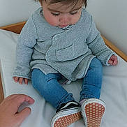 Jolene participe au concours pour gagner de l'argent avec cette photo : toddler, child, baby, cardigan, blue_jeans, shoes, indoor, white_cushion, wooden_furniture, hand, long_eyelashes, brown_hair, casual_clothing, sitting, cute, looking_down, soft_lighting, cozy, portrait, young_child