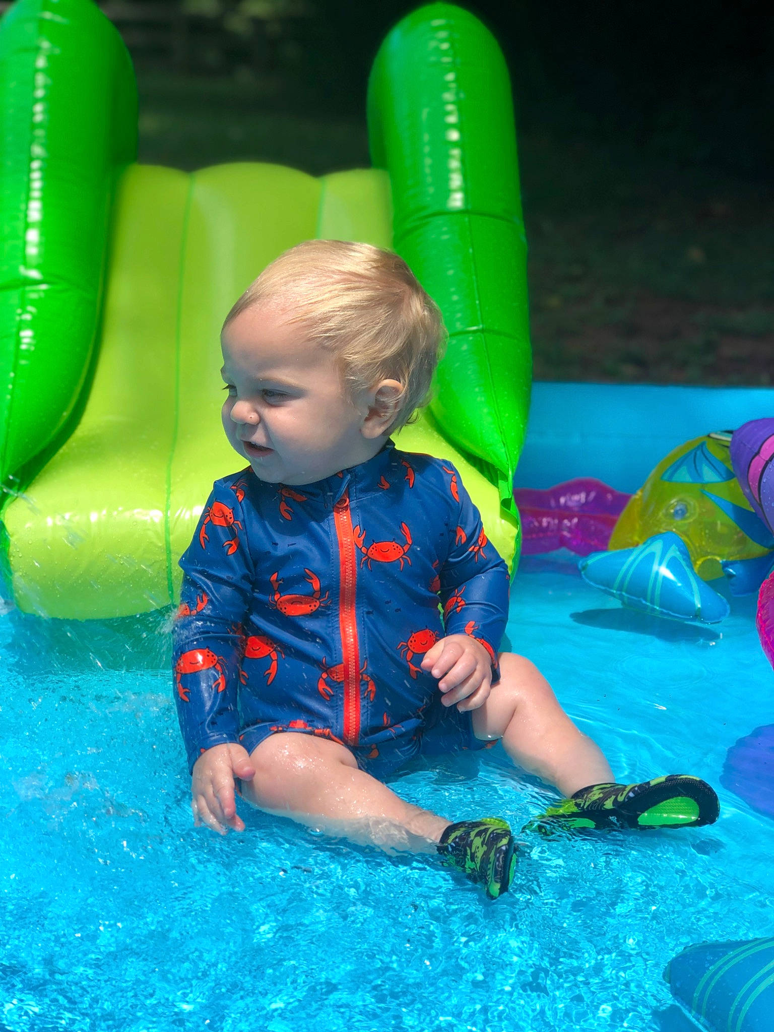 Haze is registered to the contest to win money with this photo: aqua, baby, baby_toddler_clothing, blue, bounce_house, child, electric_blue, fun, grass, green, leg, leisure, mammal, nature, outdoor_play_equipment, person, playground, recreation, sitting, summer