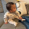 baby, child, pajamas, sitting, pacifier, couch, pillows, curly_hair, indoor, cozy, clothing, footed_pajamas, person, furniture, soft_toys, home, cute, infant, relaxed, casual