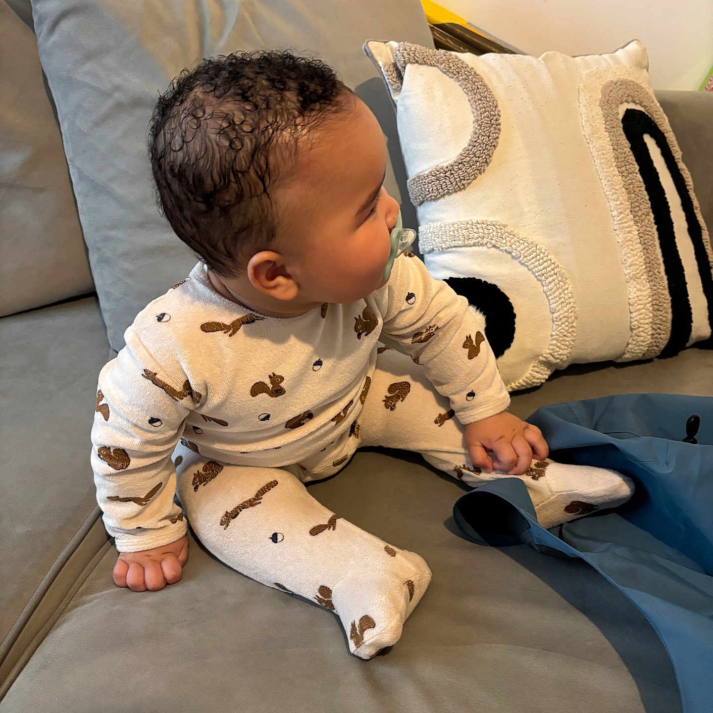 Ismaïl participe au concours pour gagner de l'argent avec cette photo : baby, child, pajamas, sitting, pacifier, couch, pillows, curly_hair, indoor, cozy, clothing, footed_pajamas, person, furniture, soft_toys, home, cute, infant, relaxed, casual
