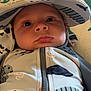 baby, child, hat, face, clothing, infant, portrait, closeup, cute, eyes, expression, zipper, pattern, babywear, headwear, indoors, cushion, fabric, soft_lighting, person