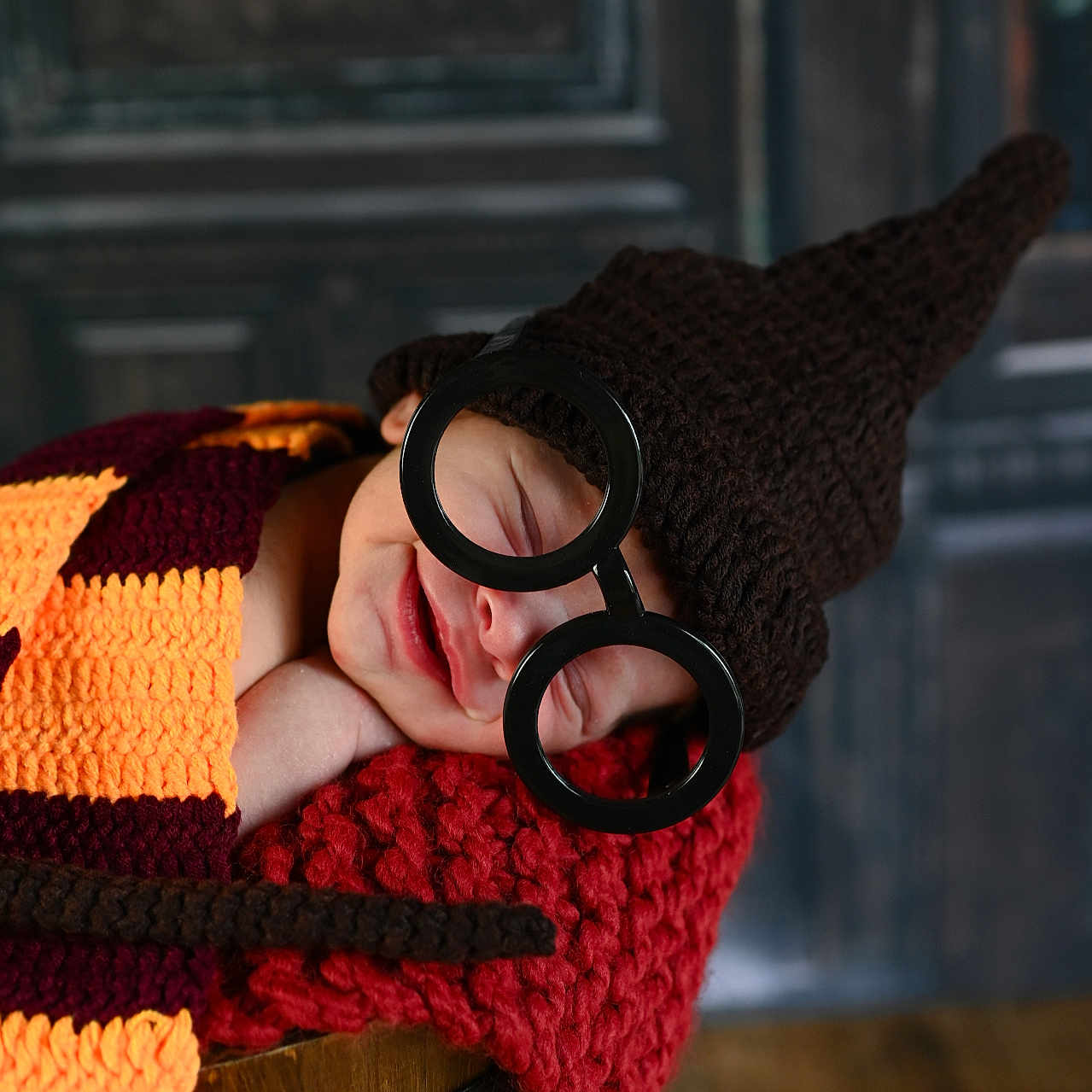 Maverick is registered to the contest to win money with this photo: baby, child, costume, cozy, cute, face, glasses, handmade, hat, headwear, indoor, knitted, novelty, portrait, resting, scarf, sleeping, smile, warm, wooden_bucket