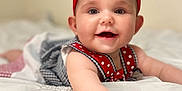 Lisa is registered to the contest to win money with this photo: arm, baby, bed, blanket, child, closeup, cute, dress, face, hand, happy, headband, indoor, infant, polka_dot, portrait, reaching, red_bow, smiling, soft_light