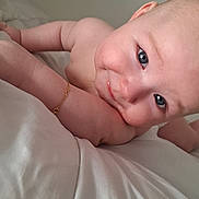 Evan participe au concours pour gagner de l'argent avec cette photo : baby, child, skin, face, arm, blue_eyes, smile, cheek, lying_down, bed, white_bed_sheet, bracelet, cute, innocent, close_up, infant, human, portrait, expression, soft_light