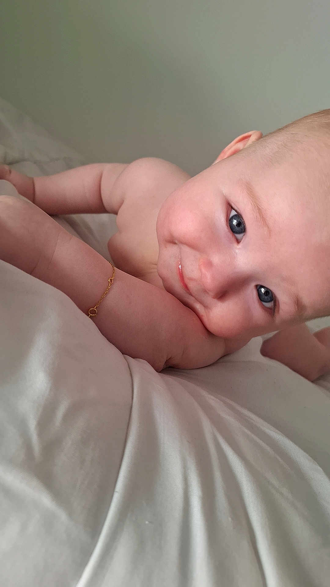 Evan participe au concours pour gagner de l'argent avec cette photo : baby, child, skin, face, arm, blue_eyes, smile, cheek, lying_down, bed, white_bed_sheet, bracelet, cute, innocent, close_up, infant, human, portrait, expression, soft_light