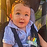 baby, child, close_up, curly_hair, eyes, face, family, golden_hour, happy, harness, infant, outdoor, portrait, seatbelt, sitting, smiling, striped_shirt, stroller, sunlight, vehicle_seat