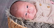 Adam is registered to the contest to win money with this photo: newborn, baby, infant, child, portrait, face, eyes, awake, lying_down, knitted_sweater, cardigan, buttons, basket, woven, faux_fur, blanket, indoor, wood_floor, photography, cozy