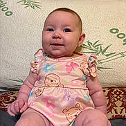 Wrenleigh is registered to the contest to win money with this photo: baby, infant, child, portrait, smiling, sitting, pink_outfit, butterfly_pattern, bear_pattern, dress, cushion, sofa, wooden_furniture, indoor, home, cozy, looking_at_camera, round_face, earring, photography
