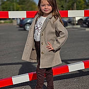 Giulia a rejoint le concours — aidez-le/la à gagner de superbes lots ! child, girl, standing, pose, coat, jacket, shirt, pants, sneakers, outdoor, parking_lot, barrier, red, white, asphalt, daylight, casual_clothing, smile, long_hair, fashion